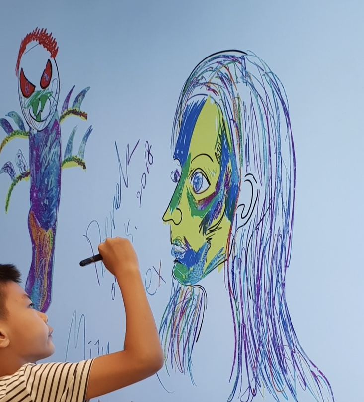 Boy drawing a colorful portrait on a digital screen.